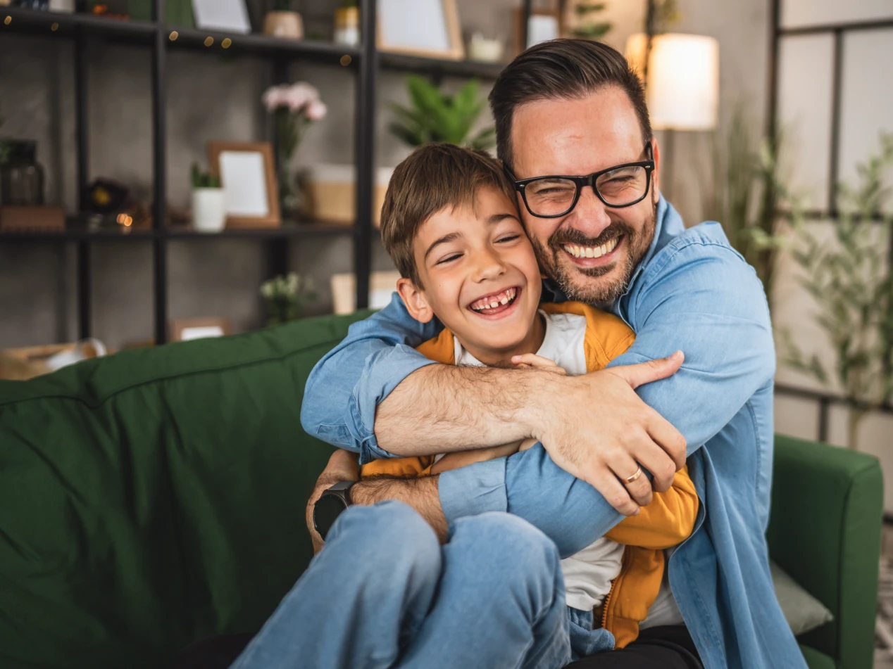 Parent hugging child, both smiling.