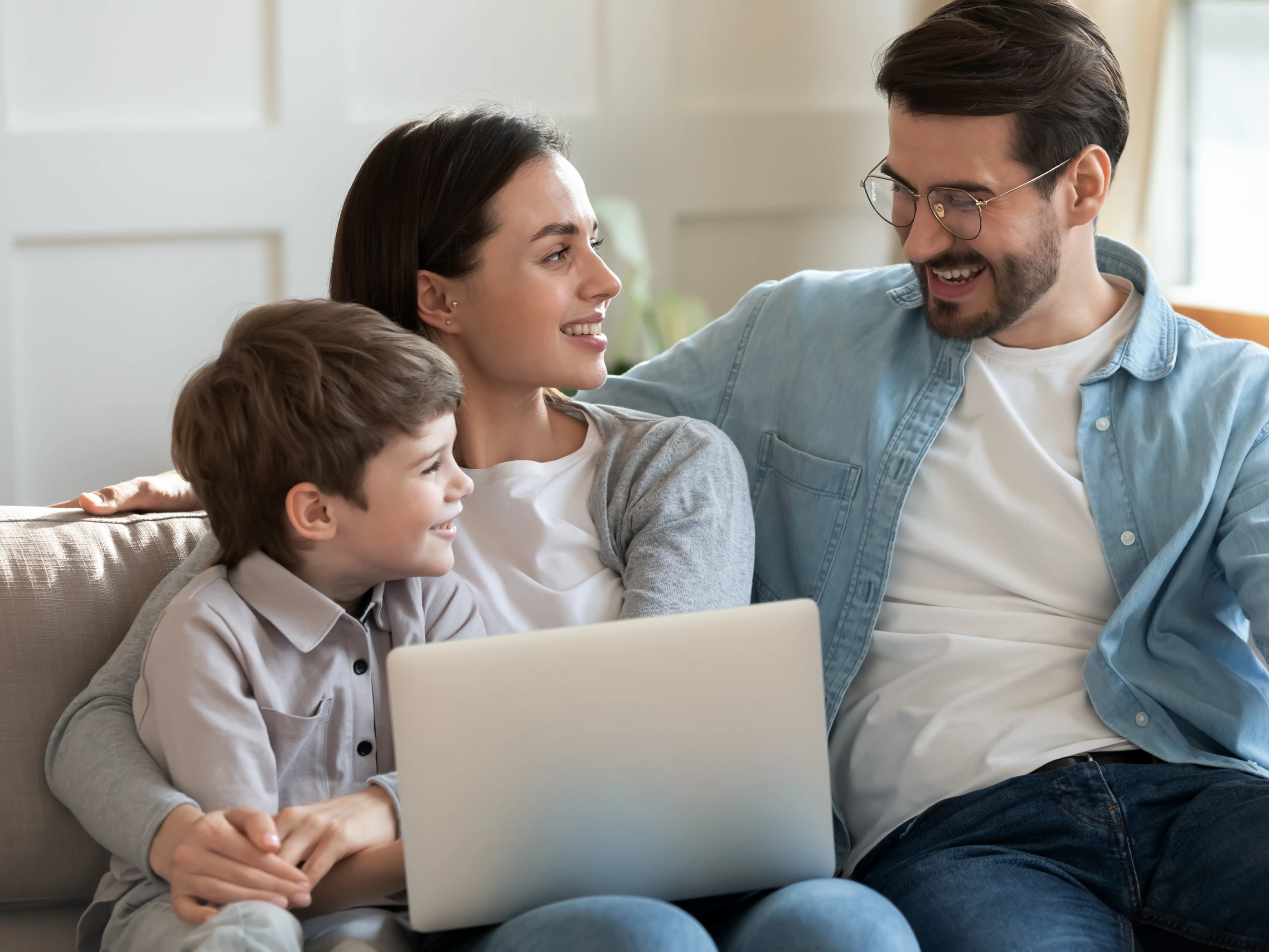 Family with child gather around a laptop and has light hearted conversation.