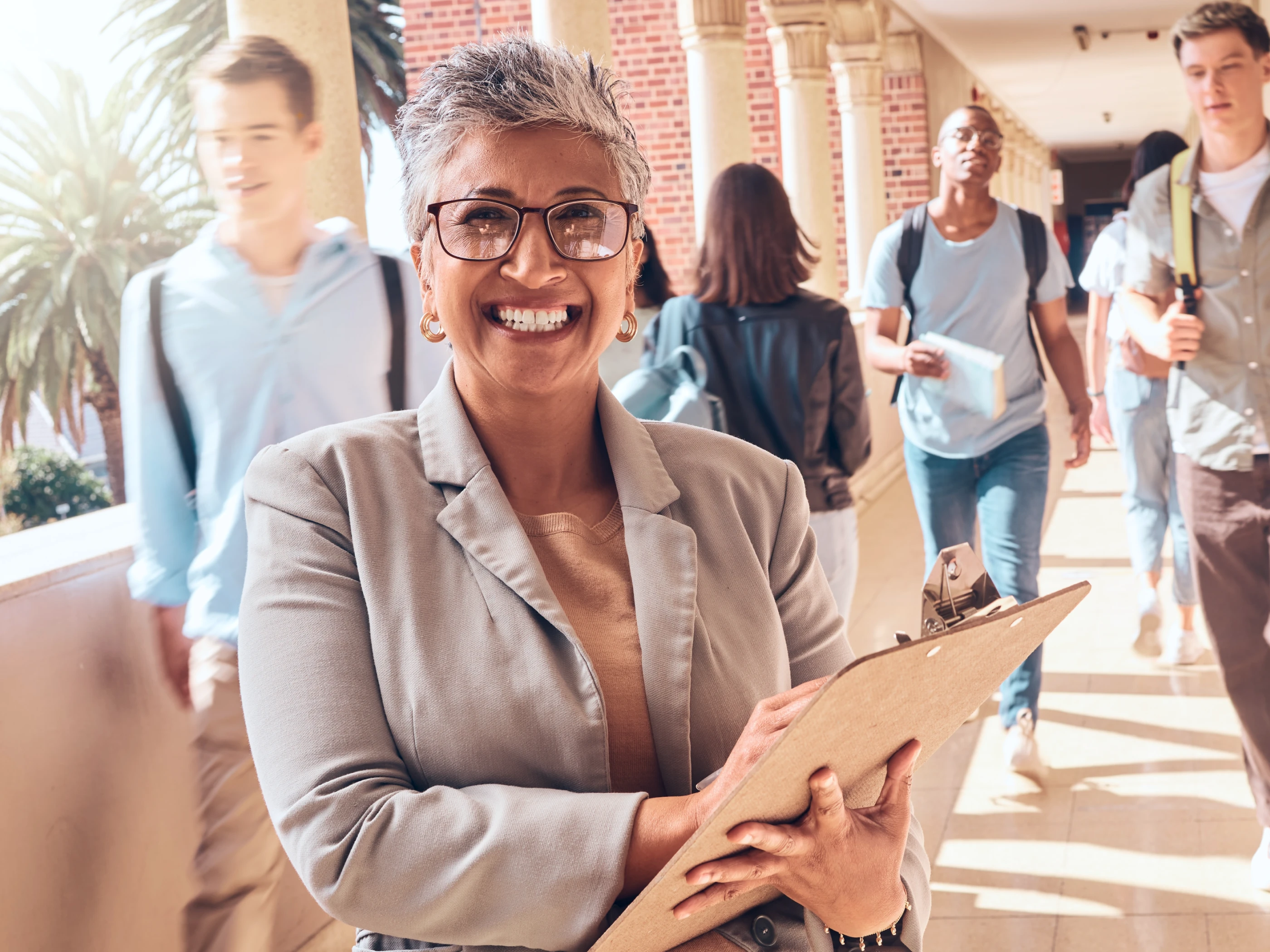 School administrator smiling with clipboard in high school environment