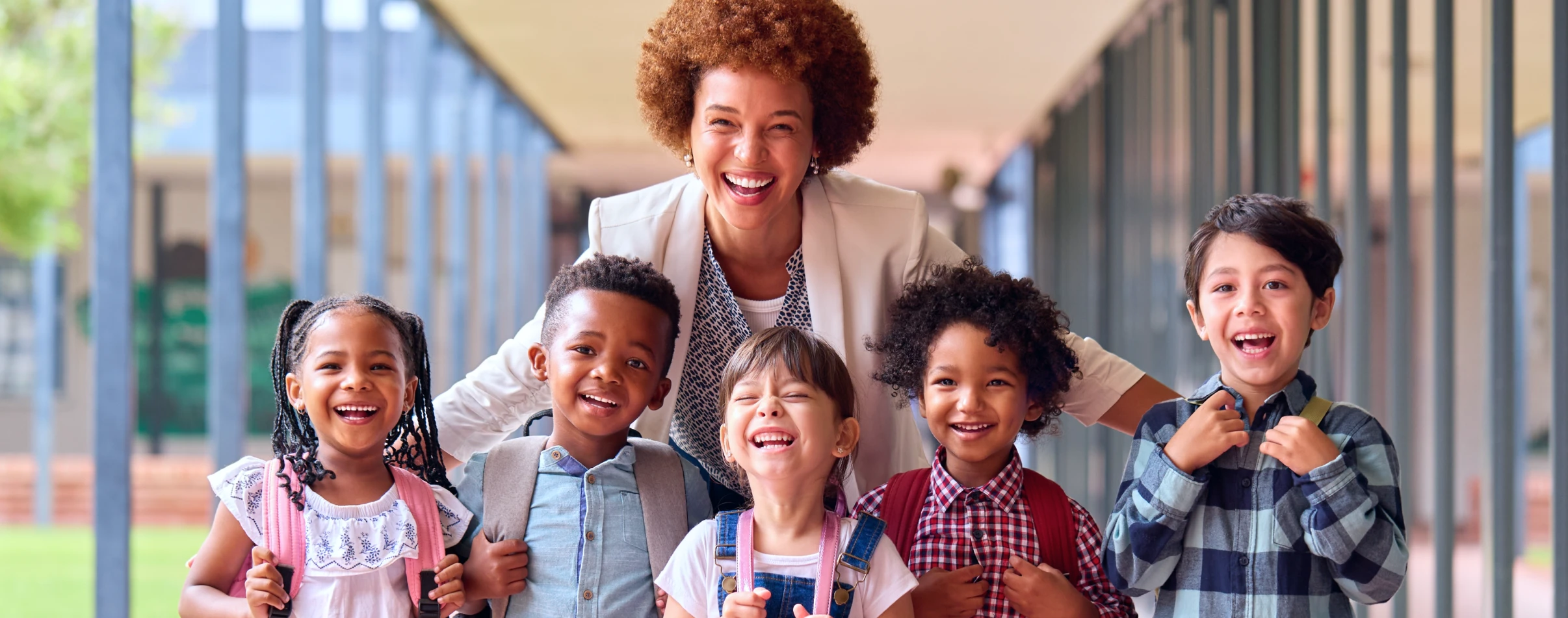 School administrator stands with a group of smiling students.