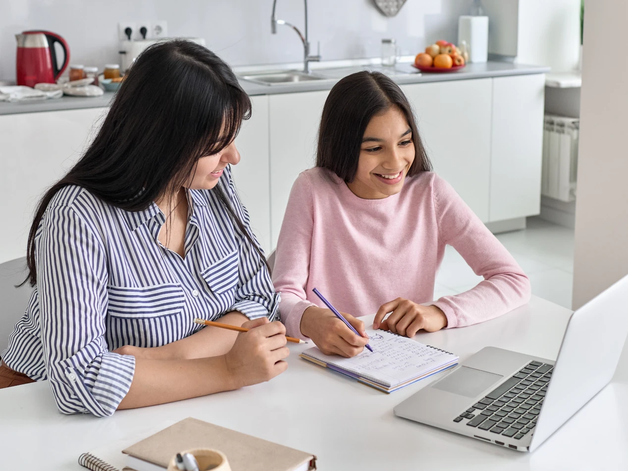 Parent and child sit at laptop together.