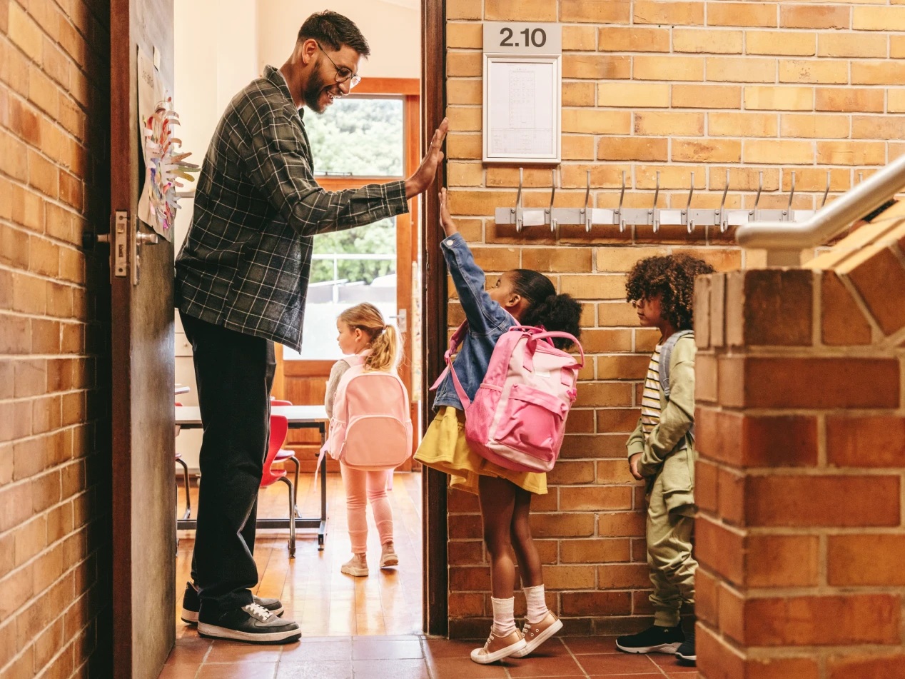 School teacher high-fiving a student.